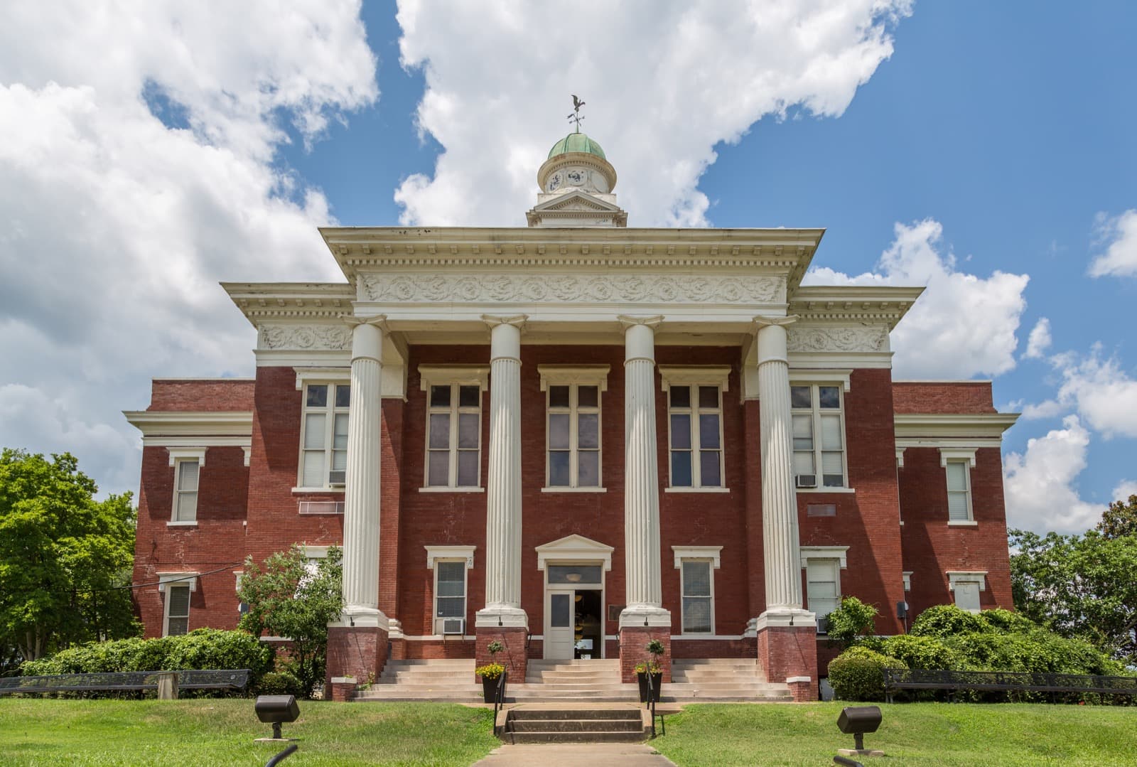 The Attala County Courthouse in Kosciusko, Mississippi, a red brick building with tall white columns and a green domed clock tower